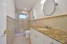 Vanity with stone countertop, integrated sink, and white cabinetry