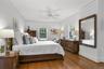 Primary bedroom suite with hardwood floors and ceiling fan.