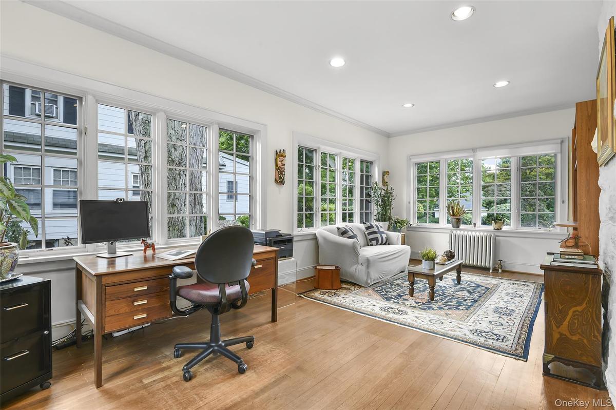 Family room has 3 walls of windows, hardwood flooring and recessed lighting.