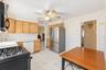 **Virtually Staged** Kitchen featuring wood-finish cabinetry, stainless steel refrigerator, white tile backsplash, and a ceiling fan with integrated l