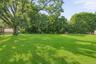 Expansive lawn with mature trees and perimeter fencing