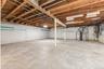 Expansive unfinished basement featuring a concrete floor, exposed wood beams, and painted block walls