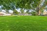 Expansive green lawn with mature trees and perimeter fencing