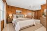 **Virtually Staged** Wood-paneled walls with light-colored carpeting, featuring a ceiling fan and a window with white trim