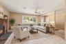 **Virtually Staged** Sophisticated living room featuring a working fireplace with brick surround, large multi-pane windows with natural light, ceiling