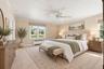 **Virtually Staged** Primary bedroom suite featuring a ceiling fan, dual nightstands with task lighting, wood-finish dresser with mirror, multiple win