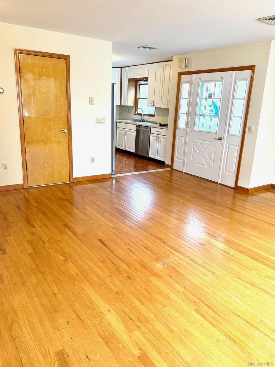 Kitchen featuring light wood finished floors, stainless steel dishwasher, white cabinets, open floor plan, and light countertops