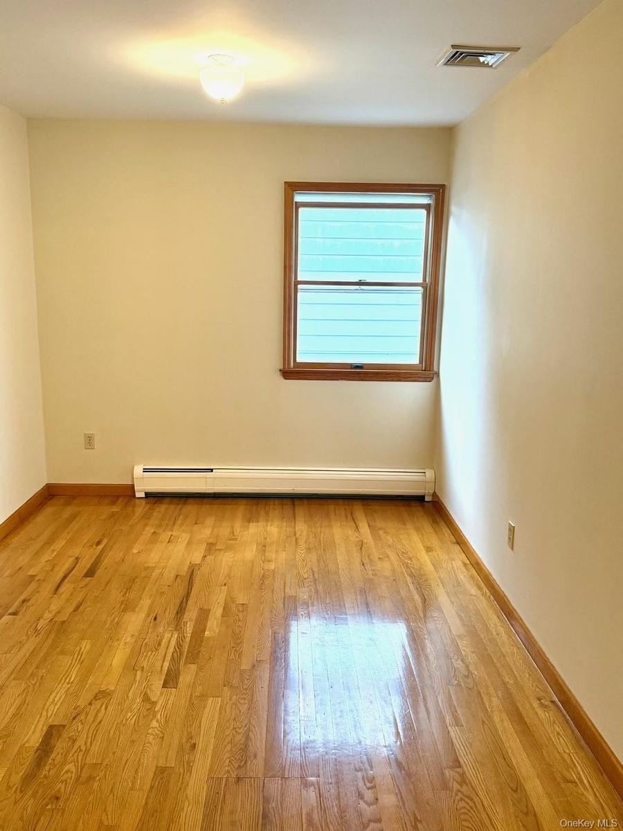 Empty room featuring light wood-style flooring and a baseboard heating unit