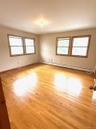 Primary bedroom featuring healthy amount of natural light, a baseboard heating unit, and light wood-style flooring