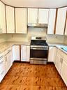 Kitchen with stainless steel gas range, white cabinets, light tile patterned floors, and light countertops