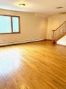 Empty room with light wood-style flooring, stairway, and a baseboard radiator