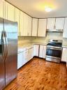 Kitchen featuring appliances with stainless steel finishes, white cabinetry, light tile patterned floors, and under cabinet range hood