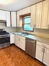 Kitchen featuring white cabinets, stainless steel appliances, light countertops, and dark tile patterned floors