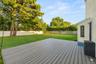 Expansive backyard featuring Trex decking, manicured lawn, mature trees, and privacy fencing. AI edited, removed all furniture.