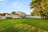 Expansive backyard featuring a manicured lawn, mature trees, and a white privacy fence