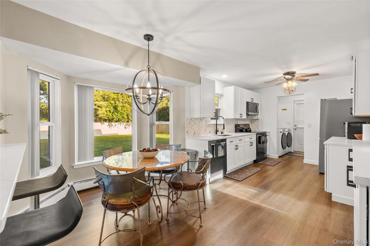 Wood-finish flooring throughout, white cabinetry, white quartz counter tops, and stainless steel appliances