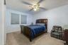 Recessed window with privacy blinds, ceiling fan with integrated lighting, and carpeted flooring. AI edited.