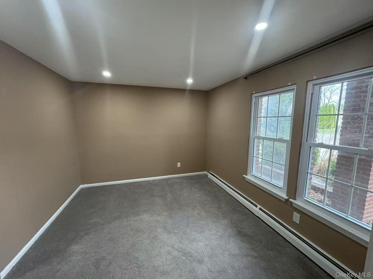 Carpeted spare room with baseboards, recessed lighting, and a baseboard radiator
