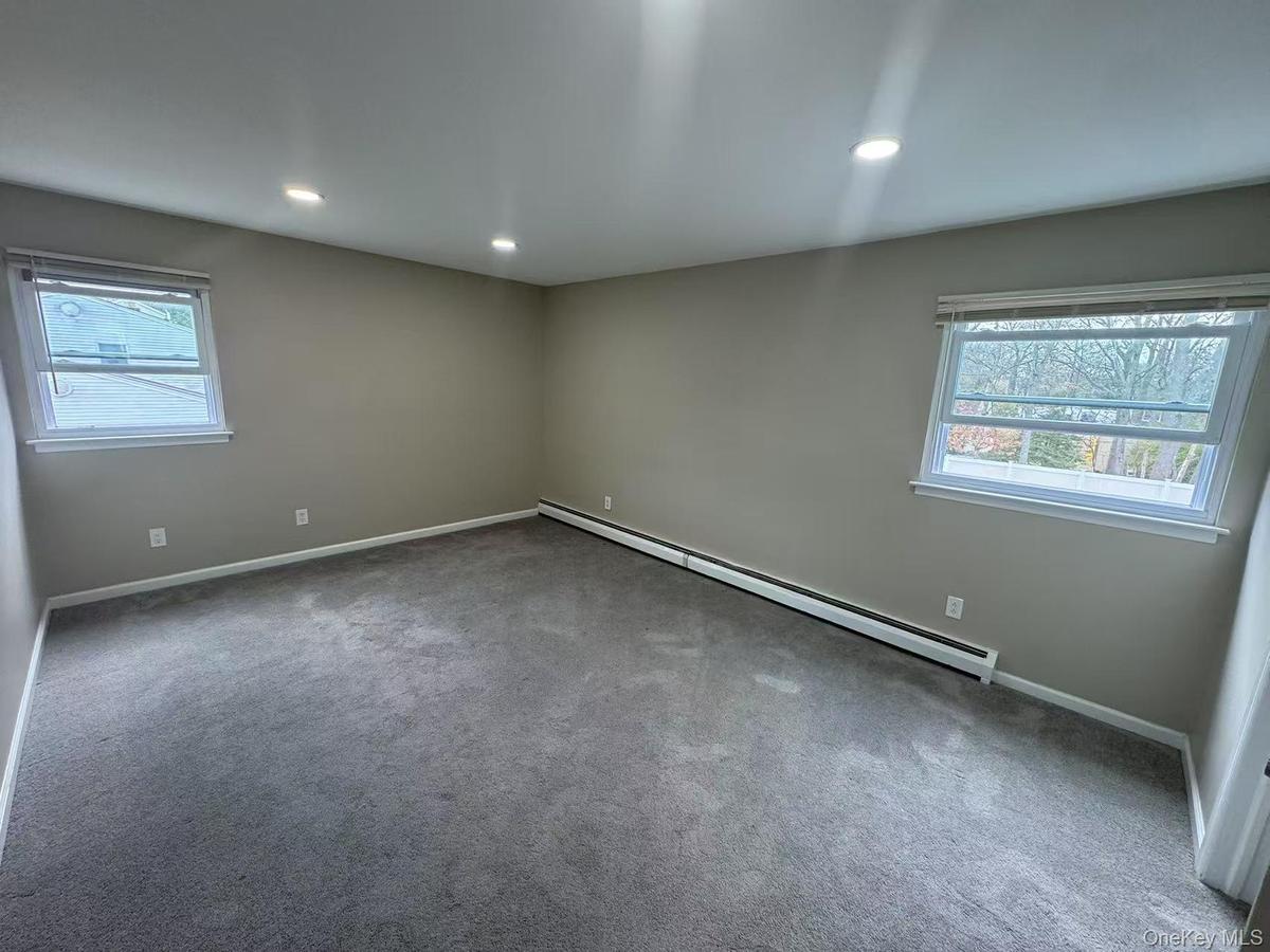 Carpeted empty room with a wealth of natural light, a baseboard heating unit, recessed lighting, and baseboards