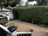 Paver patio with a tall privacy hedge and lattice fencing