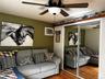 Wood-finish flooring, ceiling fan with light fixture, mirrored closet doors, and a built-in air conditioning unit