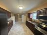 Kitchen featuring decorative backsplash, stainless steel appliances, dark brown cabinets, a sink, and a baseboard heating unit