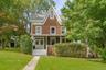 Gabled roofline, front porch, double entry doors, front lawn, and mature trees