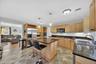 Kitchen featuring wood-finish cabinetry, dark countertops, a stainless steel refrigerator, a built-in microwave, and a center island with pendant ligh