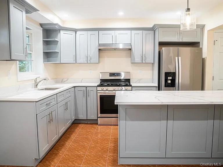 Kitchen featuring a sink, under cabinet range hood, open shelves, gray cabinetry, and appliances with stainless steel finishes