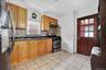 Kitchen with appliances with stainless steel finishes, brown cabinetry, decorative backsplash, under cabinet range hood, and light tile patterned floo