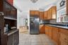 Kitchen featuring brown cabinetry, stainless steel refrigerator with ice dispenser, light tile patterned floors, and decorative backsplash