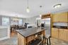 Kitchen featuring a center island with countertop seating, stainless steel refrigerator, wood-finish cabinetry, and dark countertops