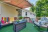 Deck with artificial turf surfacing, retractable awning, exterior door with glass inserts, and wood railing with metal balusters