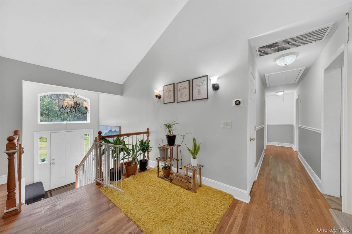 Vaulted ceiling with an arched transom window, hardwood flooring, and white painted railings