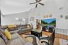 Vaulted ceilings with a ceiling fan, track lighting, wood-finish flooring, and a black metal railing