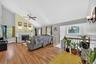 Vaulted ceiling, hardwood flooring, fireplace with mantel, ceiling fan, and staircase with wooden railing