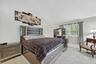 Vaulted ceiling, window with blinds and drapes, light-toned flooring, and built-in dresser with mirror