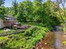 Expansive backyard featuring a multi-level wood deck, an above-ground pool, a hot tub, and a river