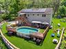 Rear exterior with solar panels, multi-level wood deck, and an above-ground pool