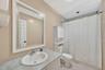 Vanity with an integrated oval sink, framed mirror, and a shower-tub combination with tile surround