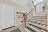 Two-story entry with a wood handrail, white balusters, tiled flooring, and a paneled entry door