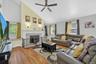 Vaulted ceiling living room featuring wood-finish flooring, a ceiling fan, and a fireplace with a detailed mantel