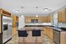 Kitchen featuring wood cabinetry, dark countertops, stainless steel appliances, a central island with pendant lighting, and patterned flooring