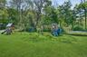 Expansive green lawn with mature trees and playsets