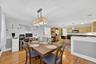 Open-concept living space featuring wood-finish flooring, a contemporary chandelier, and a kitchen with wood cabinetry, dark countertops, and stainles