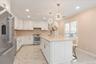 White cabinetry with gold-tone hardware and faucet taps, gas stove, stainless steel appliances, white quartz countertops, central island with storage,