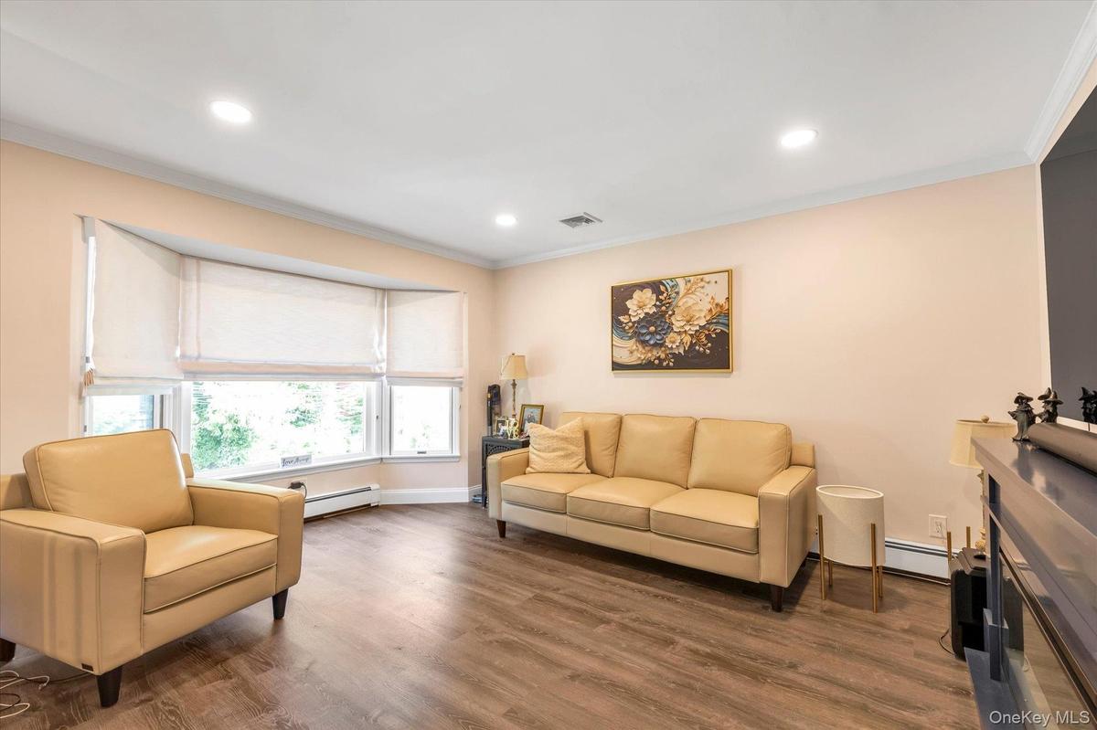 Bay window with multiple panels, wood-finish flooring, recessed ceiling lighting.