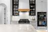 Gas range with wood-trimmed hood, glass-front black upper cabinets, and built-in wall oven and microwave.