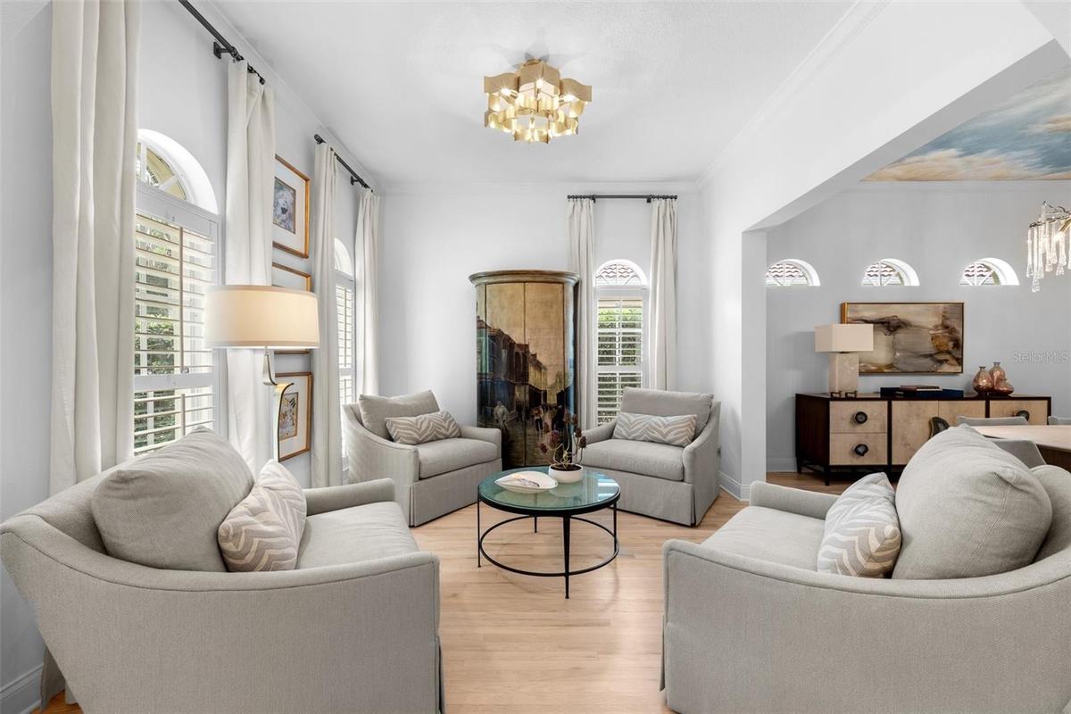 Light wood flooring, twin arched windows, and an open view into the adjoining dining room.