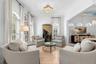 Light wood flooring, twin arched windows, and an open view into the adjoining dining room.